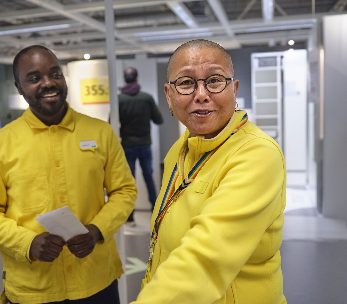 Two IKEA employees in yellow shirts smiling to the camera.