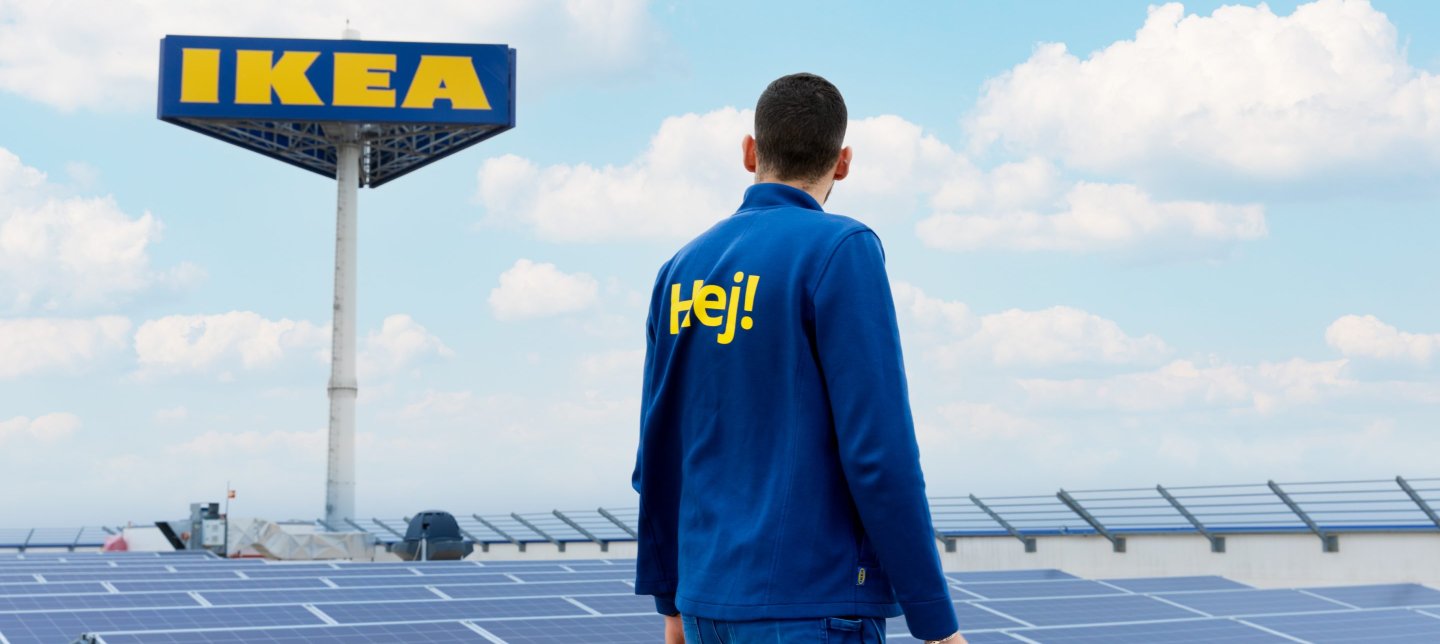 An IKEA co-worker standing on a stores roof looking over solar panels.