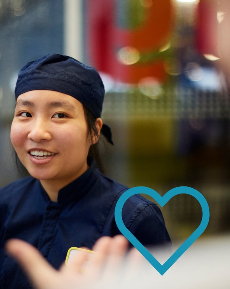 An IKEA Food co-worker wearing a blue work uniform in front of a blurred background.