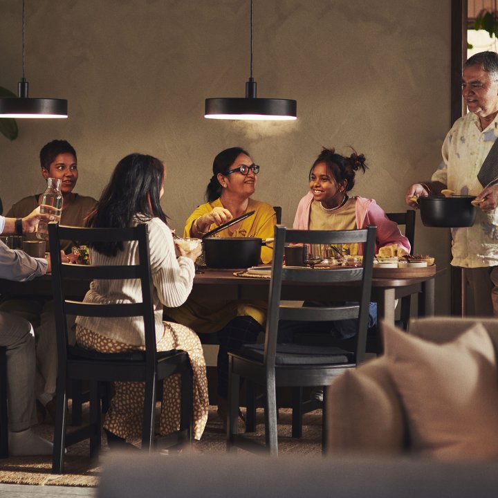 A family of six sharing a meal together in a cozy, dark dining area.