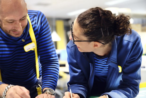 Two IKEA retail employees laughing together in the textile section.