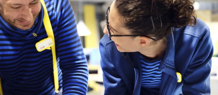 Two IKEA retail employees laughing together in the textile section.